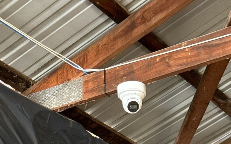 Commercial turret security camera mounted under a metal roof at a Michigan business, installed by Michigan Security Systems